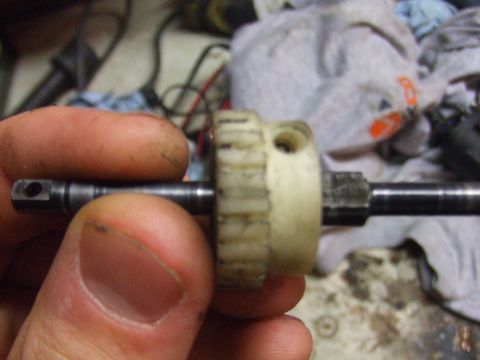 1996 Ford Bronco - A hand holds a metal shaft with a plastic gear, likely a component from a vehicle's mechanical system.