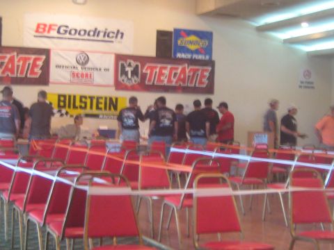 1996 Ford Bronco - A group of people stand behind tables in front of various sponsor banners at an event.