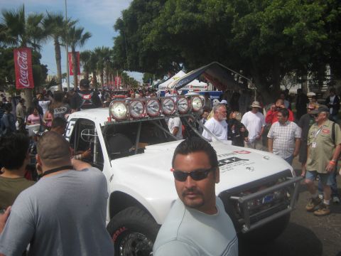 1996 Ford Bronco - A white off-road truck with numerous lights is parked outdoors, surrounded by spectators and tents.