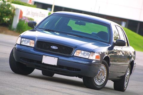 1998 Ford Crown Victoria - A blue 1998 Ford Crown Victoria is shown from a low angle, highlighting its front grille and headlights.