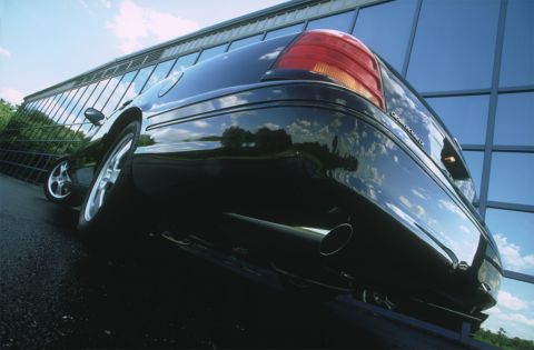 1998 Ford Crown Victoria - Dramatic low ground-level 3/4 rear shot of a black Ford sedan wearing a "CROWN VICTORIA LX" badge on the trunk, with a large polished exhau…