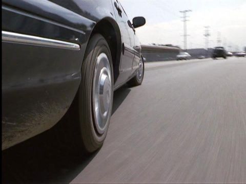 1998 Ford Crown Victoria - Side view of a car in motion on a highway, with other vehicles visible ahead.
