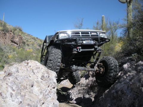 1986 Toyota Hilux - Modified 1986 Toyota Hilux navigating a rocky trail in a desert environment.