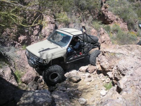 1986 Toyota Hilux - Customized Toyota pickup truck tackling a challenging off-road trail.