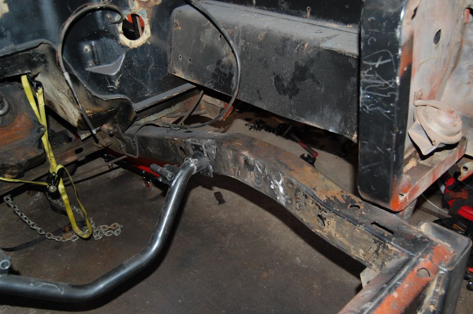 Vehicle frame with yellow straps and chains, showing rust and metalwork