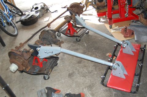 1994 Ford Bronco - Vehicle axle assemblies are staged on creeper dollies and jack stands in a garage setting.