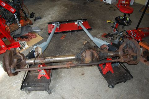 1994 Ford Bronco - A disassembled front axle assembly rests on shop equipment in a garage setting.