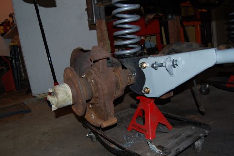 1994 Ford Bronco - Vehicle suspension part being worked on, supported by jack stands in a garage.