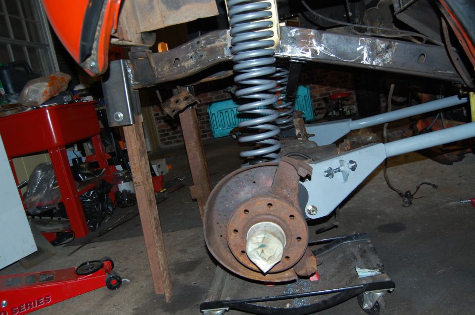 close-up of vehicle's front suspension and frame with orange fender piece visible