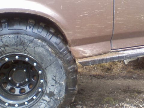 1993 Ford Bronco - Close-up of the front wheel and fender of a 1993 Ford Bronco, covered in mud.