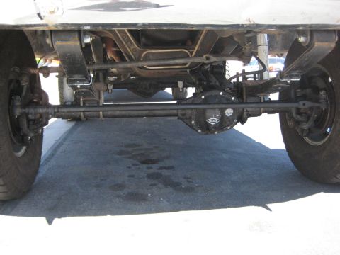 1996 Ford Bronco - Close-up view of the undercarriage, focusing on the steering and suspension system of a vehicle, a differential cover with a skull emblem.
