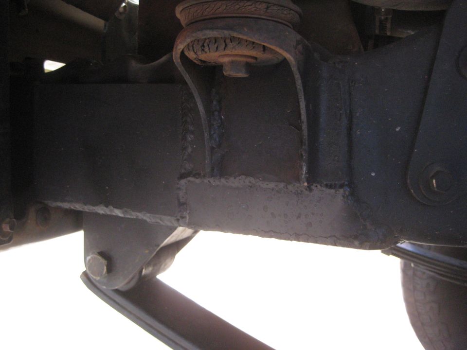 Close-up of vehicle suspension components with Supermotors.net watermark