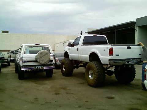 1996 Ford Bronco - Two trucks are parked outside a building under a cloudy sky.
