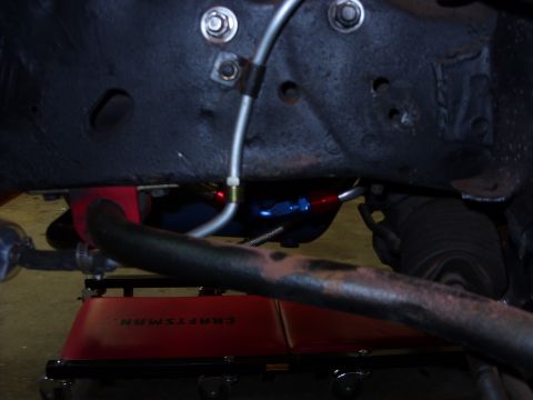 1978 Ford Mustang II - Close-up view of power steering lines and the rack and pinion assembly, with a red creeper visible below.