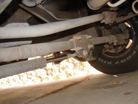 1973 Ford Ranchero - A close-up view of the steering linkage and a tire from underneath a vehicle, with visible text on the tire.
