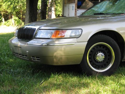 2000 Mercury Grand Marquis - The front grille and headlight assembly of a gold Mercury Grand Marquis is visible.