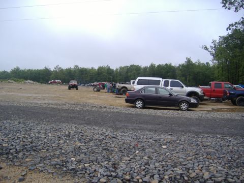 1988 Ford Bronco - A variety of vehicles are parked in an outdoor lot under an overcast sky.