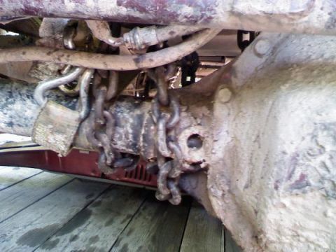 1988 Ford Bronco - Chains are secured to the undercarriage of a vehicle, suggesting off-road use or modification.