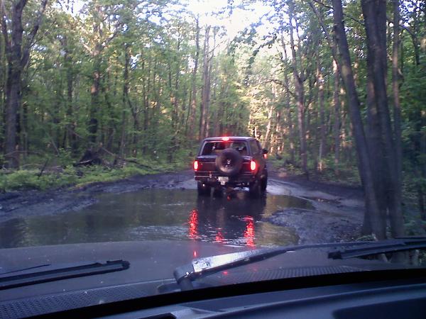 1988 Ford Bronco rear view driving through muddy forest road