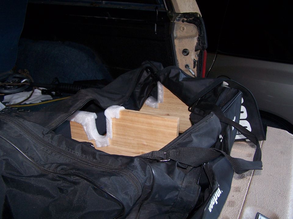 Black duffel bag with wooden supports inside an open vehicle cargo area
