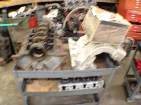 1996 Ford Bronco - Engine block and cylinder head are displayed on a cart, with a box of oil resting on the intake manifold.