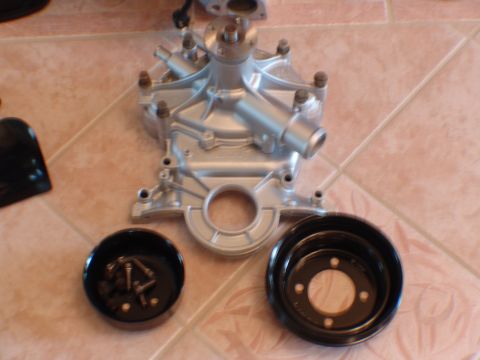 1996 Ford Bronco - A silver water pump and two black pulleys are laid out on a tiled floor.