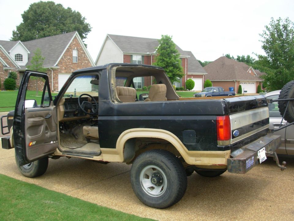 Black and tan Ford Bronco with top removed in a driveway