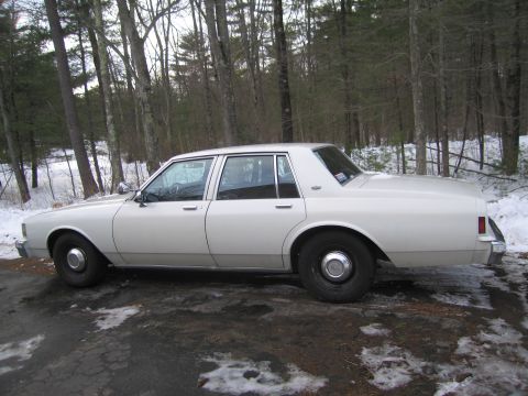 2001 Ford Crown Victoria - This white sedan has a boxy body style typical of 1980s American sedans.