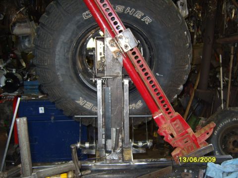1989 Ford Bronco - A hi-lift jack is shown next to a spare tire, likely in a workshop or garage setting.