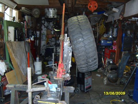 1989 Ford Bronco - A cluttered garage scene with a large tire hanging and various tools and equipment visible.