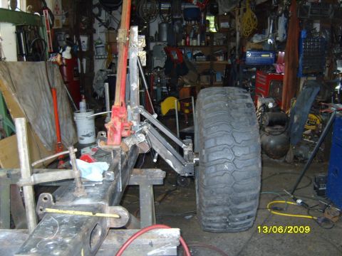 1989 Ford Bronco - A large off-road tire and suspension components are visible in a cluttered workshop setting.