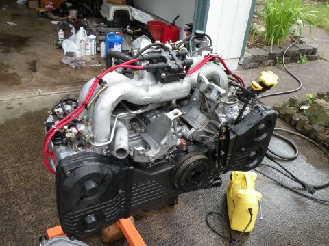 1998 Subaru Legacy - A Subaru EJ22 engine, likely from a 1998 model, is displayed on an orange stand outdoors.