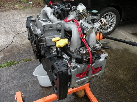 1998 Subaru Legacy - Subaru EJ22 engine on an engine stand, with a black car wheel in the background.