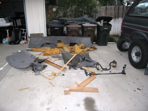 1986 Ford Bronco - Interior components are scattered on the ground next to a black SUV, suggesting a disassembly or repair process.