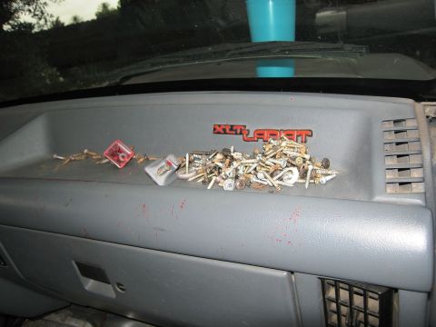 1986 Ford Bronco - Dashboard of a 1986 Ford Bronco interior, showing the XLT Lariat trim badge and a collection of screws.