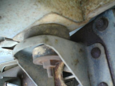 1990 Ford Bronco - Detail of a rusty suspension mount, likely from the underside of a vehicle.