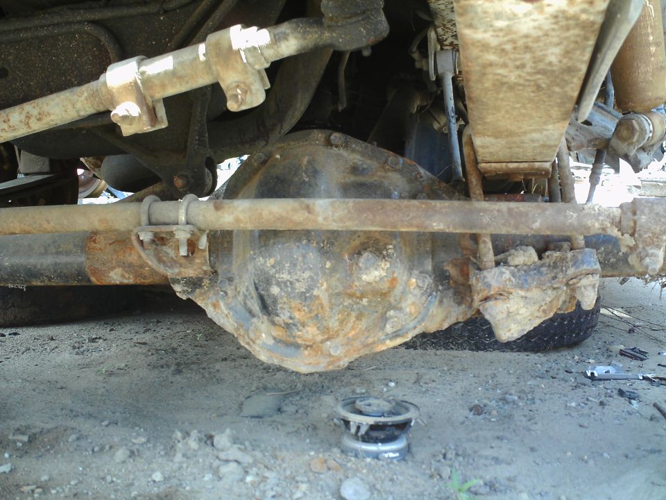 Undercarriage view of a rusty differential and suspension parts