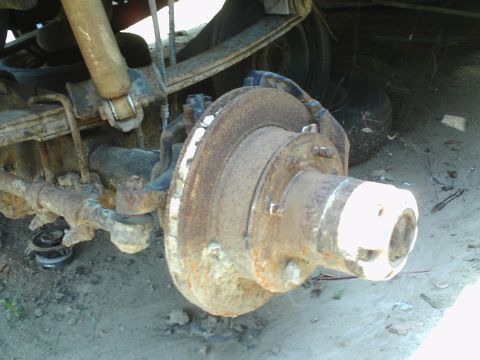 1990 Ford Bronco - Close-up of a heavily rusted front axle hub and brake assembly, likely from an older vehicle.