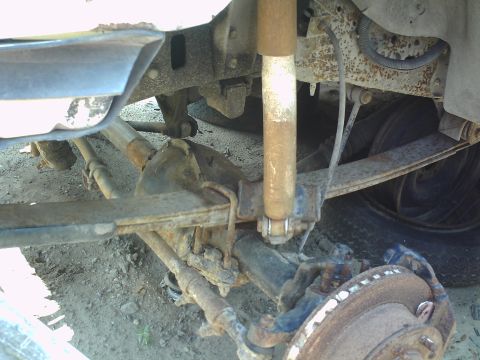 1990 Ford Bronco - Close-up view of the rear suspension and axle assembly, showing leaf springs and a shock absorber.