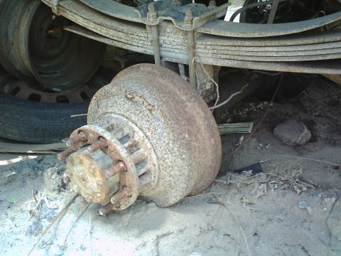 1990 Ford Bronco - A heavily rusted brake drum and hub assembly is visible, with leaf springs from a vehicle overhead.