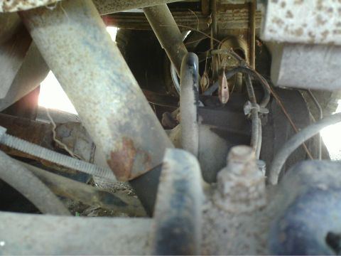 1990 Ford Bronco - Close-up of the undercarriage, focusing on suspension and brake system components.