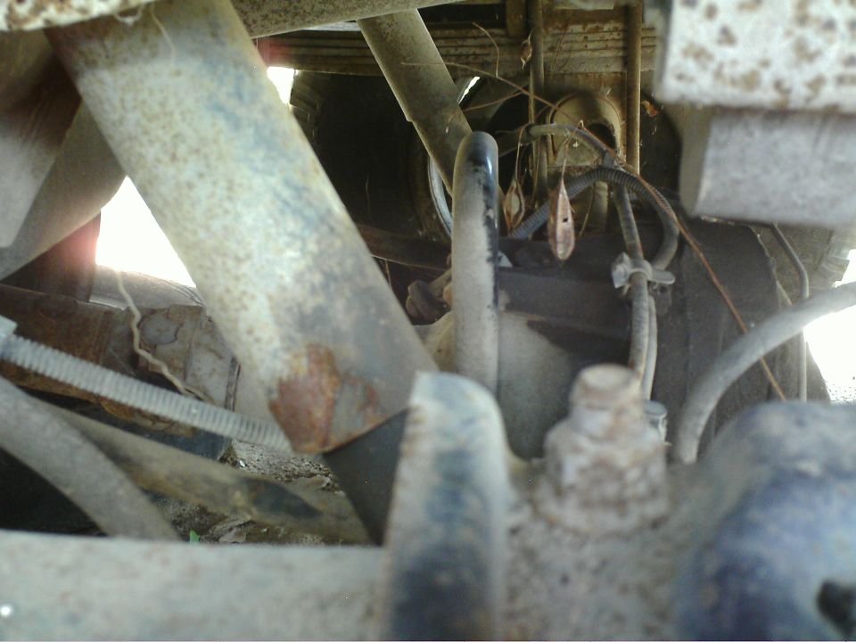 Undercarriage view showing suspension parts, leaf springs, and brake lines