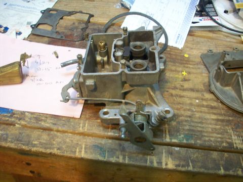 1978 Jeep CJ5 - Carburetor assembly and gasket on a wooden workbench, possibly for a vehicle repair.
