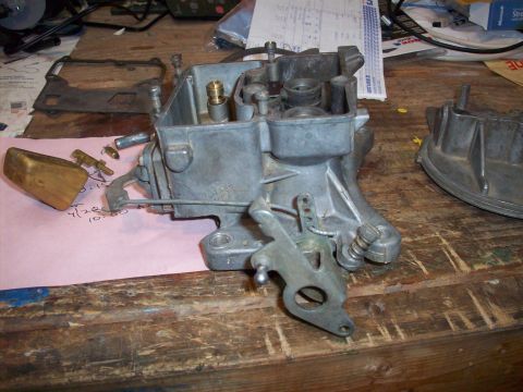 1978 Jeep CJ5 - A disassembled carburetor sits on a wooden workbench next to a pink paper with handwritten notes.