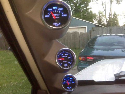1995 Ford Bronco - Three gauges are visible inside a vehicle, with a green car parked outside.