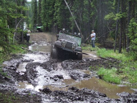 1990 Ford Bronco - Off-roading adventure turns into a muddy challenge for a Jeep Wrangler on a forest trail.
