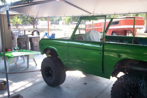 1976 Ford Bronco - A green 1976 Ford Bronco body sits in a garage, appearing to be in the process of restoration.
