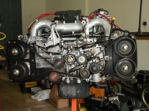 1998 Subaru Legacy - A close-up view of an engine, likely a Subaru EJ series, showing its intricate timing belt system and various pulleys.