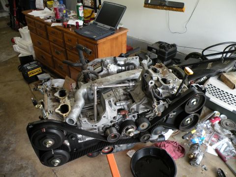 1998 Subaru Legacy - A disassembled Subaru EJ25 engine is shown, with its timing belt and pulleys visible.