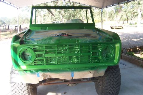 1976 Ford Bronco - A green 1976 Ford Bronco is partially covered with plastic sheeting as it sits under a tent, likely during a paint job.